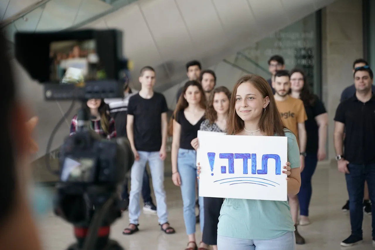 צילום קבוצתי עם משתתפים המחזיקים שלט תודה